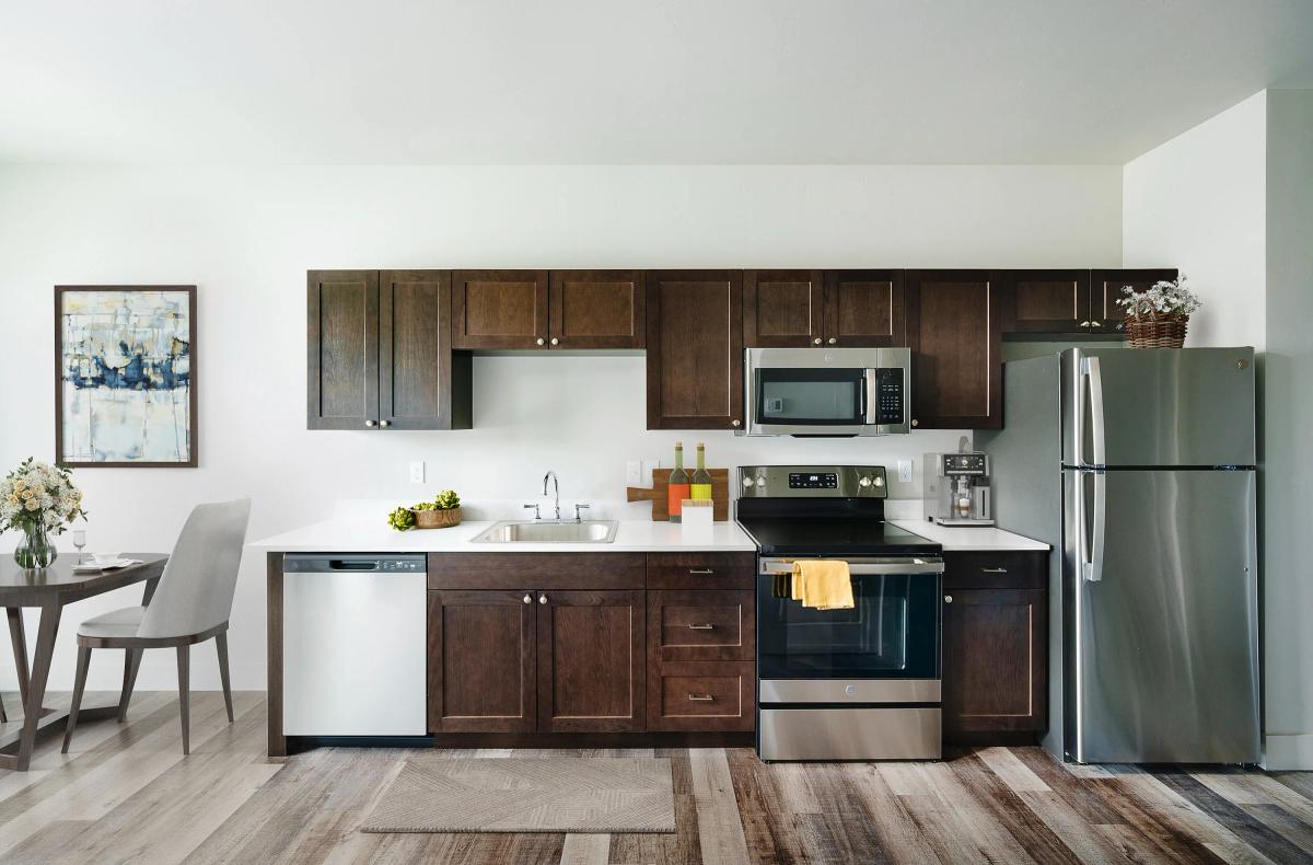 Modern kitchen with dark wood cabinets, stainless steel appliances, and a cozy dining area.